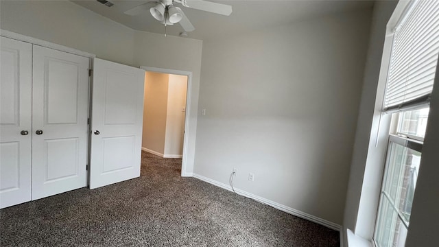 unfurnished bedroom with a closet, baseboards, a ceiling fan, and dark colored carpet