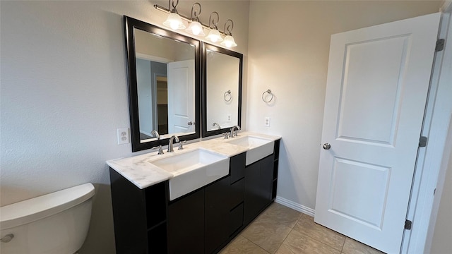 full bath featuring double vanity, a sink, tile patterned floors, and toilet