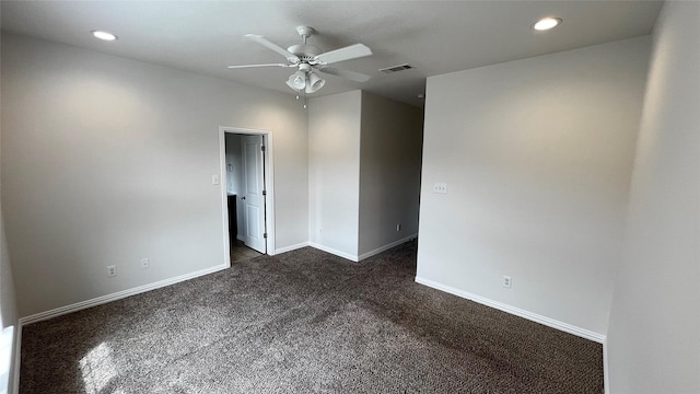 empty room featuring visible vents, baseboards, ceiling fan, and dark carpet