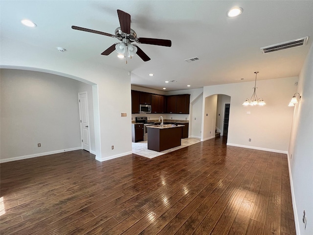 unfurnished living room featuring visible vents, arched walkways, dark wood-style flooring, and a sink