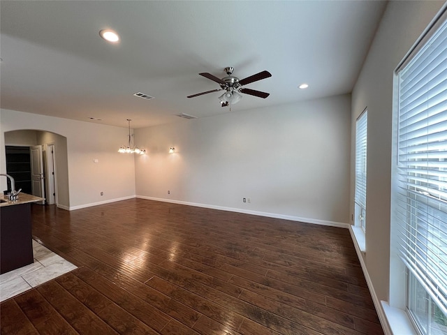 unfurnished living room featuring visible vents, arched walkways, wood finished floors, ceiling fan with notable chandelier, and recessed lighting