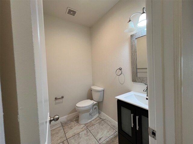 half bath featuring vanity, baseboards, toilet, and visible vents