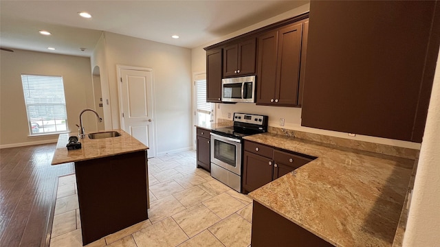 kitchen featuring a sink, appliances with stainless steel finishes, baseboards, and dark brown cabinets