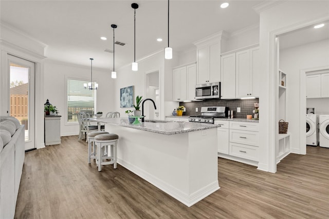 kitchen featuring a sink, appliances with stainless steel finishes, wood finished floors, and washer and dryer