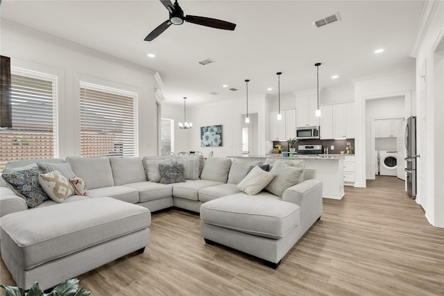 living area with washer / dryer, ornamental molding, ceiling fan with notable chandelier, and light wood-type flooring