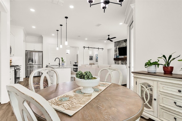 dining room featuring ornamental molding, light wood-style flooring, recessed lighting, and a barn door