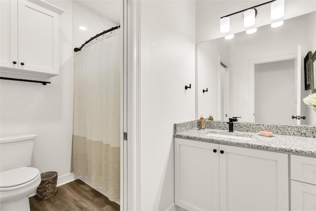 full bath featuring vanity, baseboards, wood finished floors, and toilet