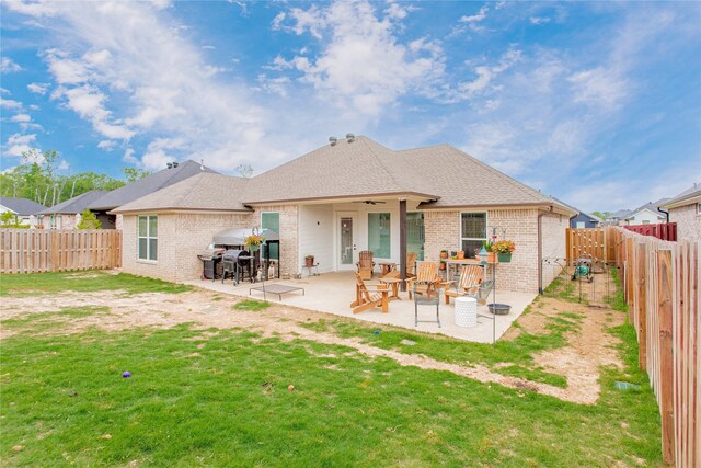 rear view of property with brick siding, a fenced backyard, a patio area, and a lawn