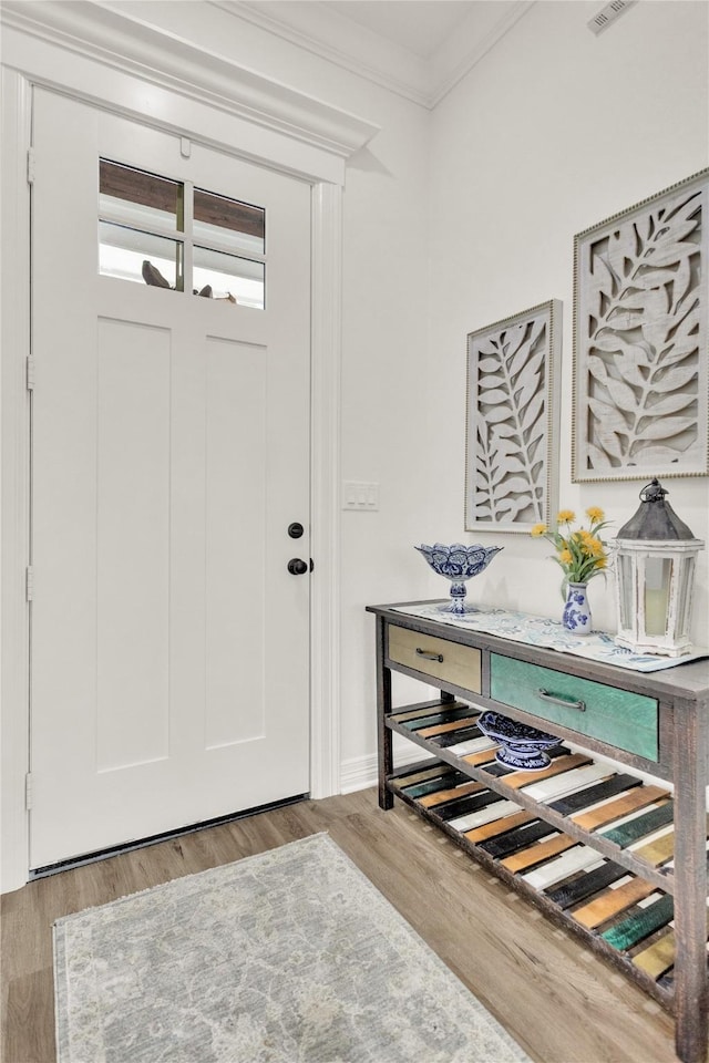 foyer featuring crown molding and wood finished floors