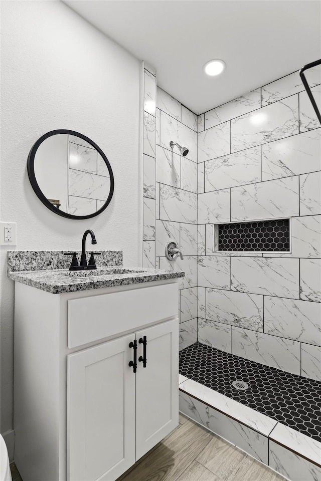 full bathroom featuring recessed lighting, a tile shower, and vanity