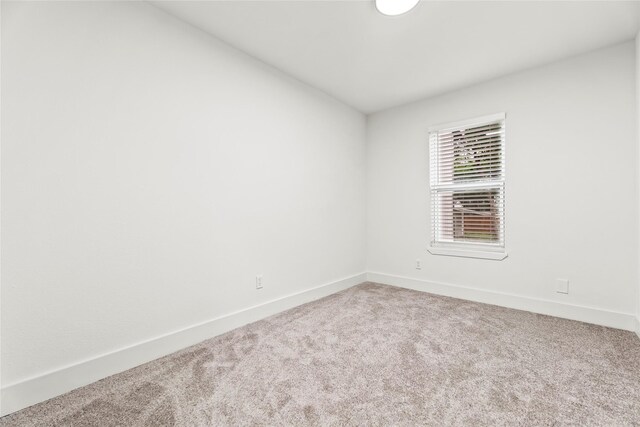 carpeted empty room featuring baseboards
