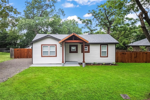 view of front facade featuring a shingled roof, fence, and a front yard