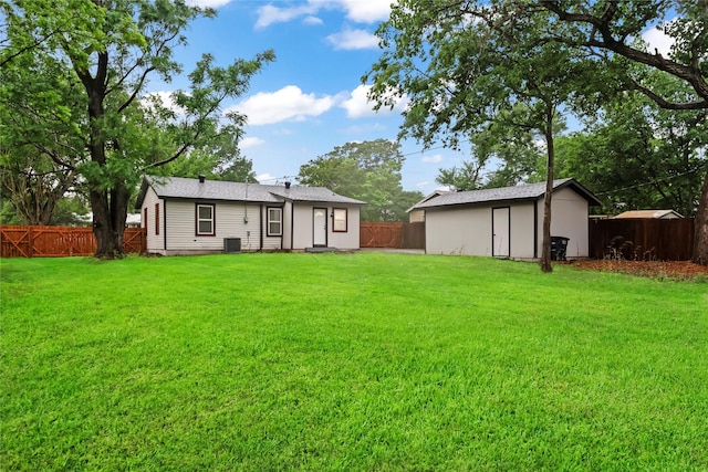 rear view of house featuring a fenced backyard, central AC unit, an outdoor structure, and a yard