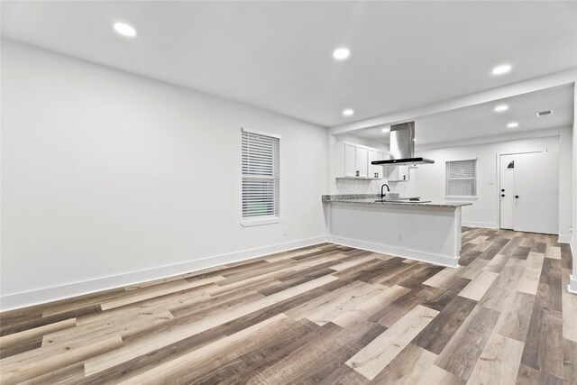 kitchen with white cabinets, a peninsula, recessed lighting, and island range hood