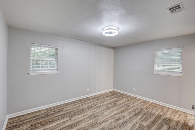 spare room with baseboards, wood finished floors, and visible vents