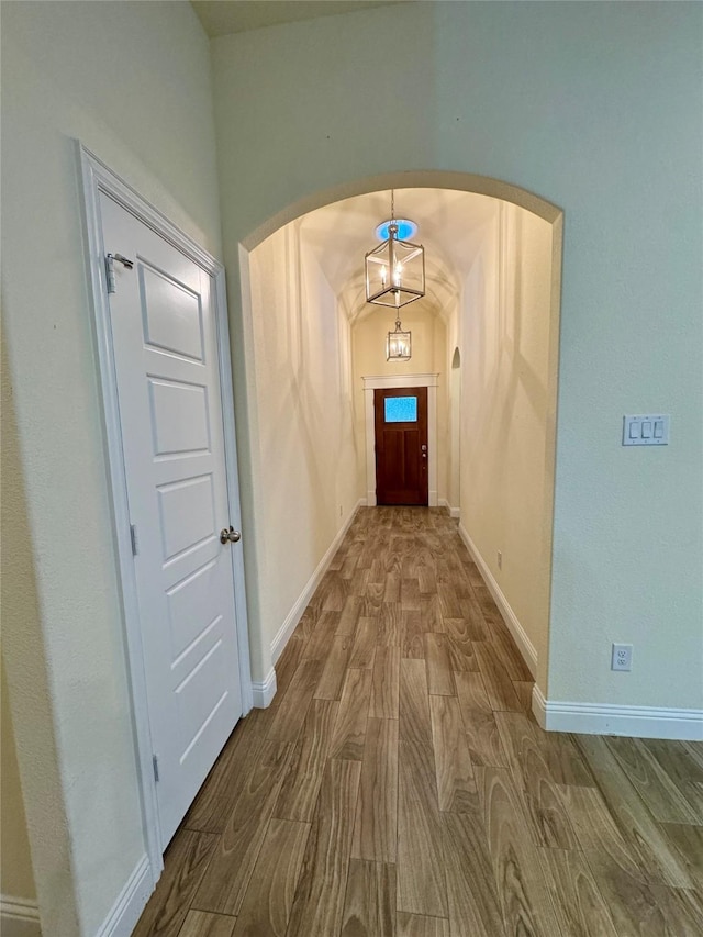 doorway to outside featuring arched walkways, baseboards, and wood finished floors