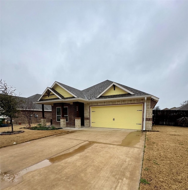 craftsman inspired home with fence, roof with shingles, brick siding, a garage, and concrete driveway