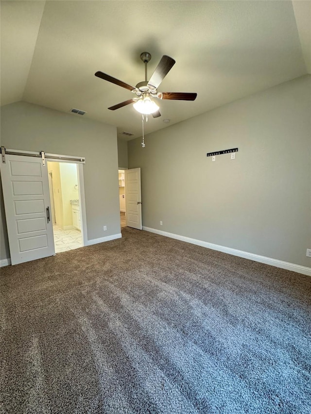 unfurnished bedroom with light colored carpet, a barn door, baseboards, ensuite bathroom, and visible vents
