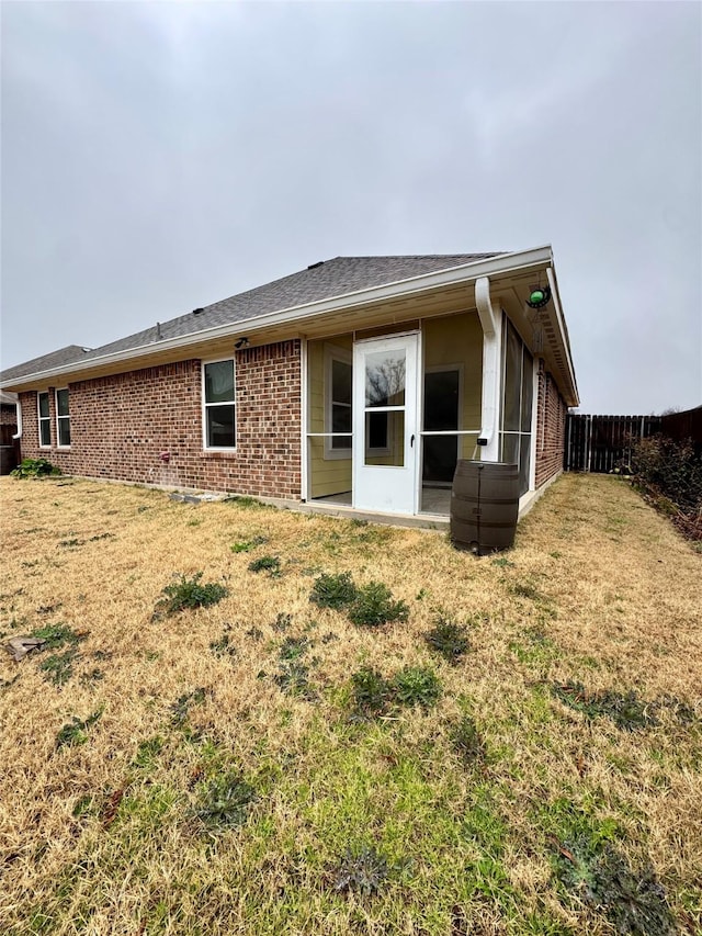 back of property featuring a lawn, brick siding, and fence