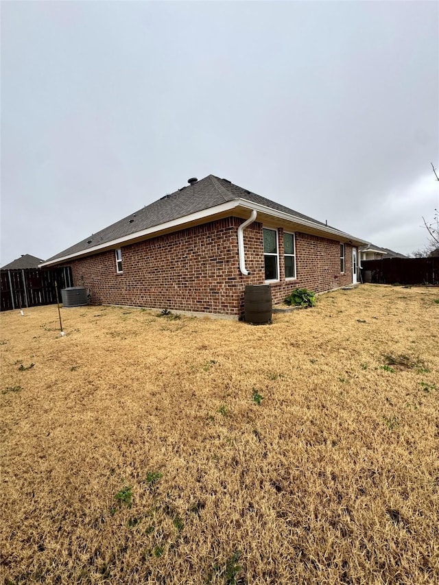 view of side of home featuring central AC unit, a yard, and brick siding