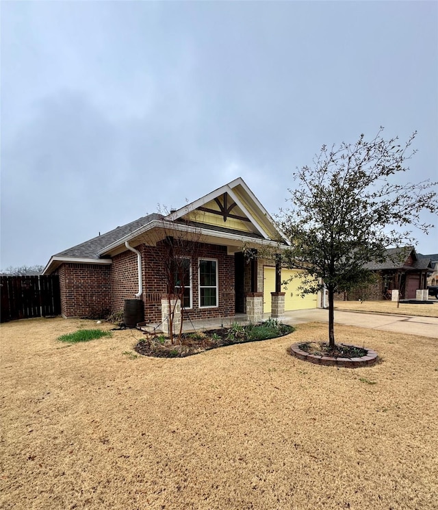 view of front of house with a garage, fence, brick siding, central AC unit, and driveway