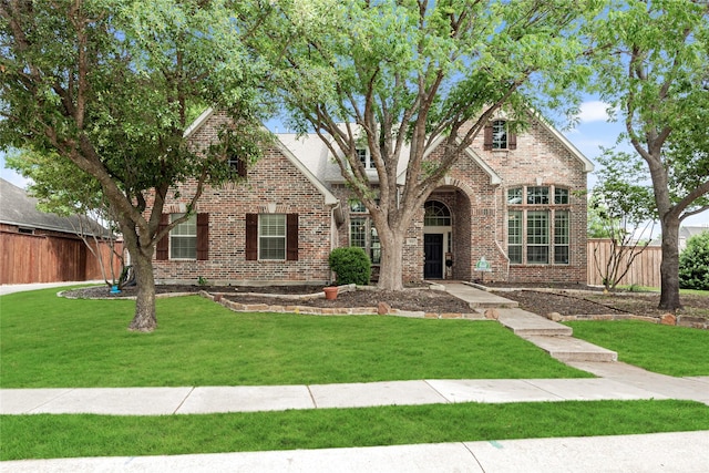 view of front of property with fence, a front yard, and brick siding