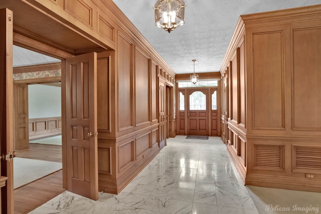mudroom featuring a decorative wall, marble finish floor, and a notable chandelier