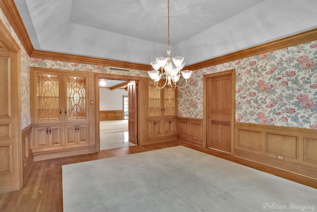 unfurnished dining area featuring an inviting chandelier, visible vents, wood finished floors, wallpapered walls, and a wainscoted wall