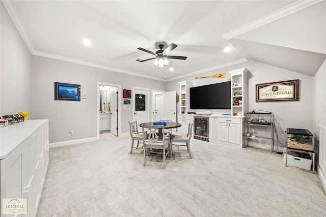 dining room with ceiling fan, baseboards, wine cooler, ornamental molding, and light carpet
