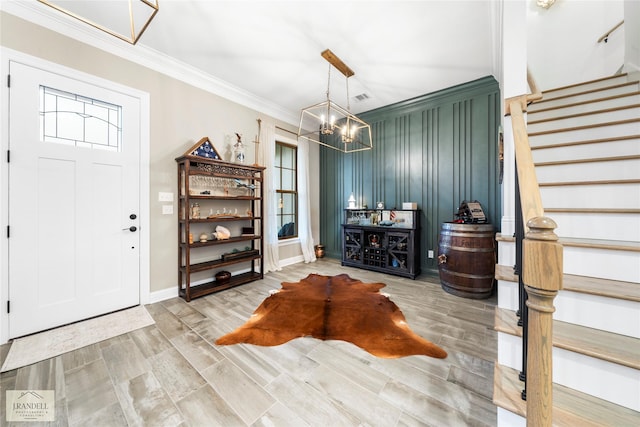 entrance foyer featuring wood finished floors, stairway, baseboards, a notable chandelier, and ornamental molding