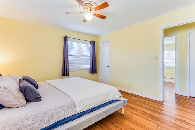 bedroom featuring crown molding, a ceiling fan, baseboards, and light wood finished floors