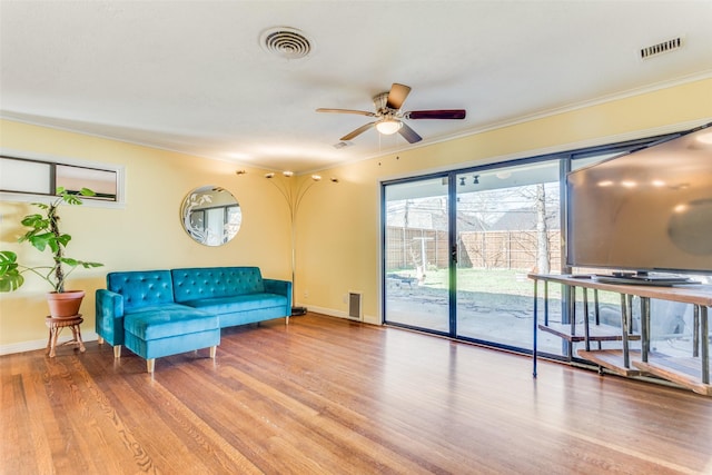 living room featuring visible vents, ornamental molding, and wood finished floors