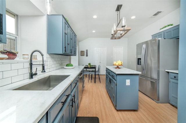 kitchen with a kitchen island, stainless steel appliances, tasteful backsplash, a sink, and blue cabinetry