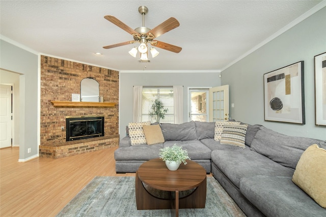living room with ornamental molding, a ceiling fan, wood finished floors, and a brick fireplace