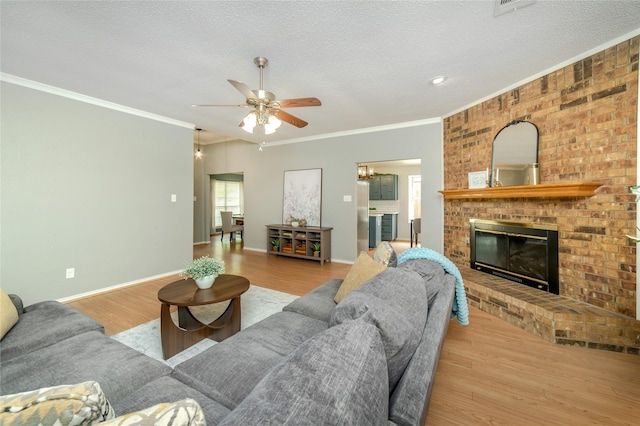living area with a fireplace, a textured ceiling, ceiling fan with notable chandelier, wood finished floors, and ornamental molding