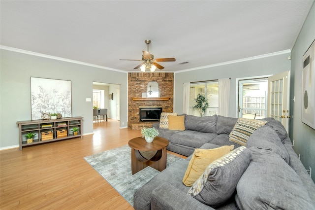 living area with light wood-style floors, a ceiling fan, crown molding, and visible vents