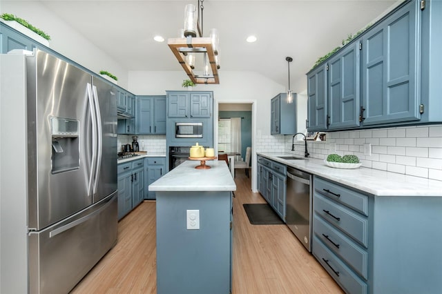 kitchen featuring decorative backsplash, a center island, blue cabinets, a sink, and stainless steel appliances
