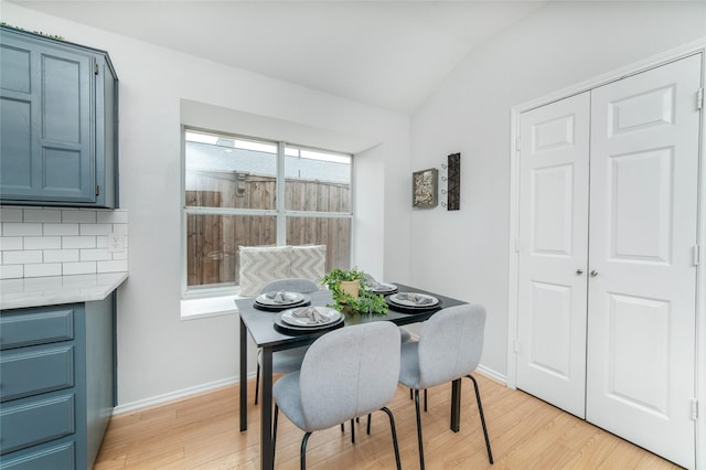 dining room with baseboards, vaulted ceiling, and light wood-style flooring