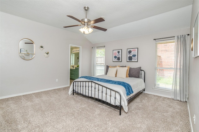 carpeted bedroom with baseboards, a ceiling fan, ensuite bath, and vaulted ceiling