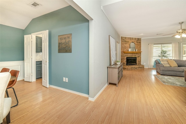 living area featuring a ceiling fan, light wood-style floors, visible vents, and a fireplace