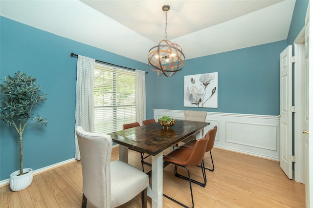 dining room with an inviting chandelier, wainscoting, and light wood finished floors