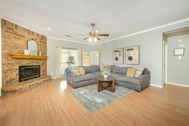 living area with crown molding, wood finished floors, a fireplace, baseboards, and ceiling fan