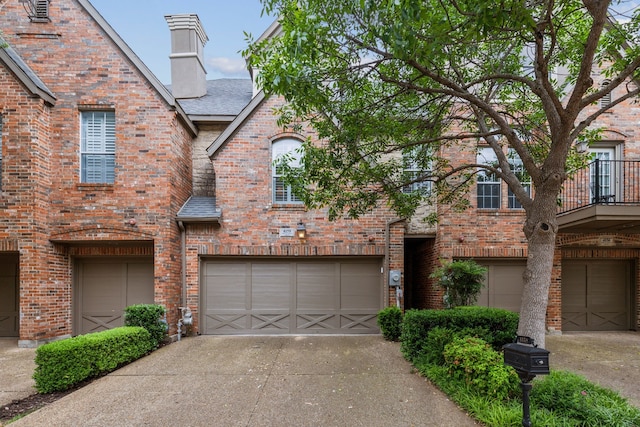 view of front of home with a chimney, roof with shingles, brick siding, concrete driveway, and an attached garage