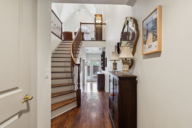 interior space featuring ceiling fan, dark wood-style floors, stairway, and a towering ceiling