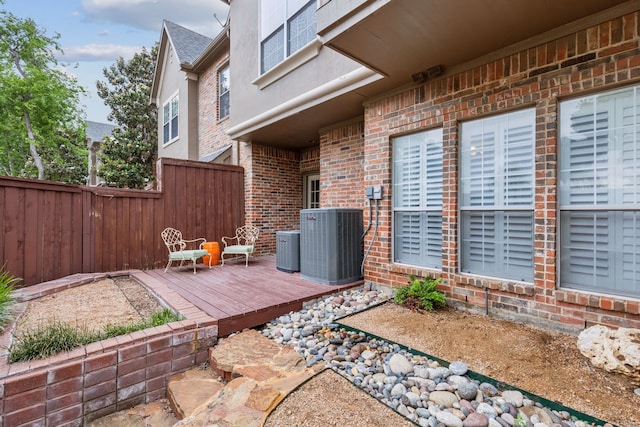 exterior space with fence, a wooden deck, and cooling unit