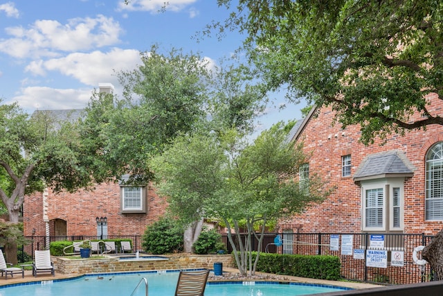 pool with a community hot tub and fence