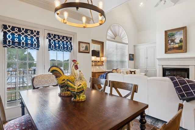 dining area featuring a glass covered fireplace, a chandelier, and high vaulted ceiling