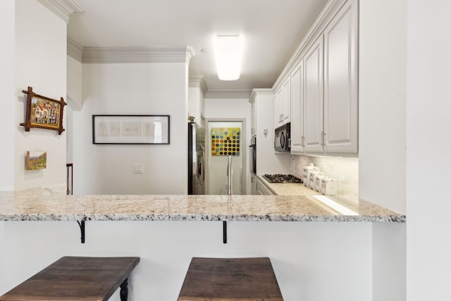 kitchen with a kitchen breakfast bar, black appliances, a peninsula, and white cabinets