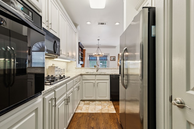 kitchen featuring wood finished floors, white cabinetry, a sink, backsplash, and black appliances