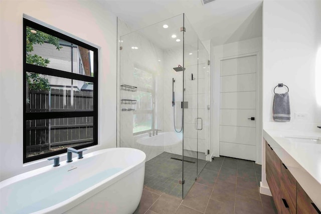 full bath with double vanity, a freestanding tub, a shower stall, tile patterned floors, and recessed lighting
